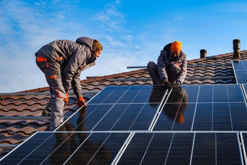 two men installing solar panels on roof