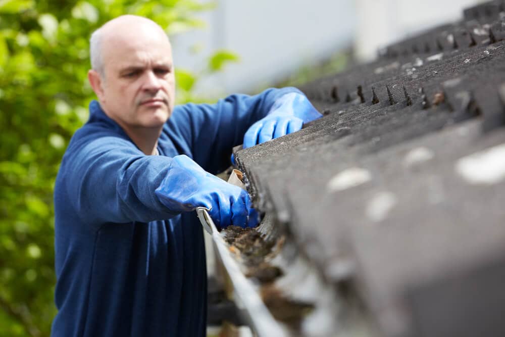 man removing debris in gutter