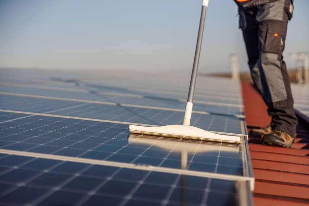 closeup of worker cleaning rows of solar panels